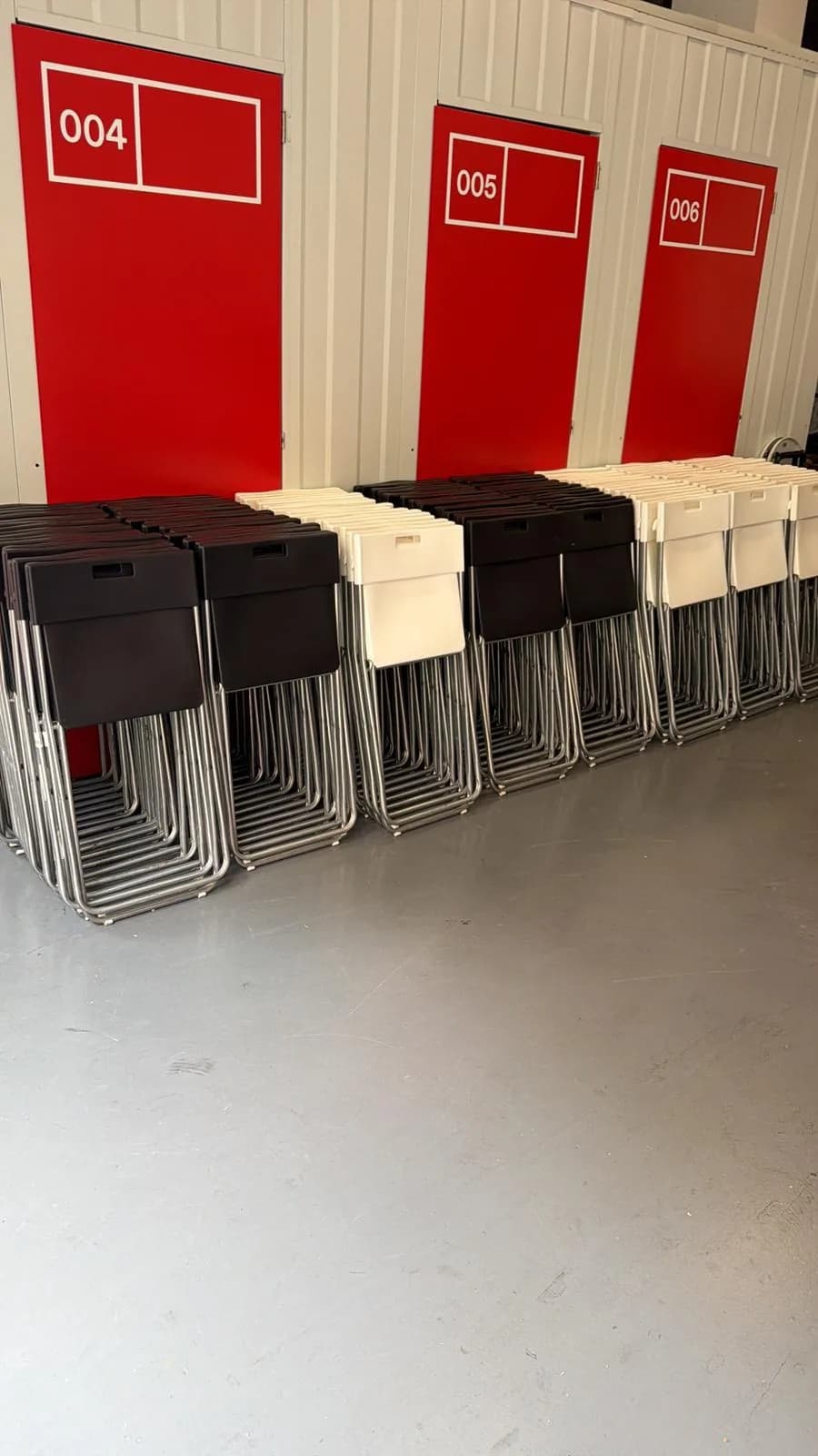 Cadires plegables apilades al magatzem, a punt per repartir