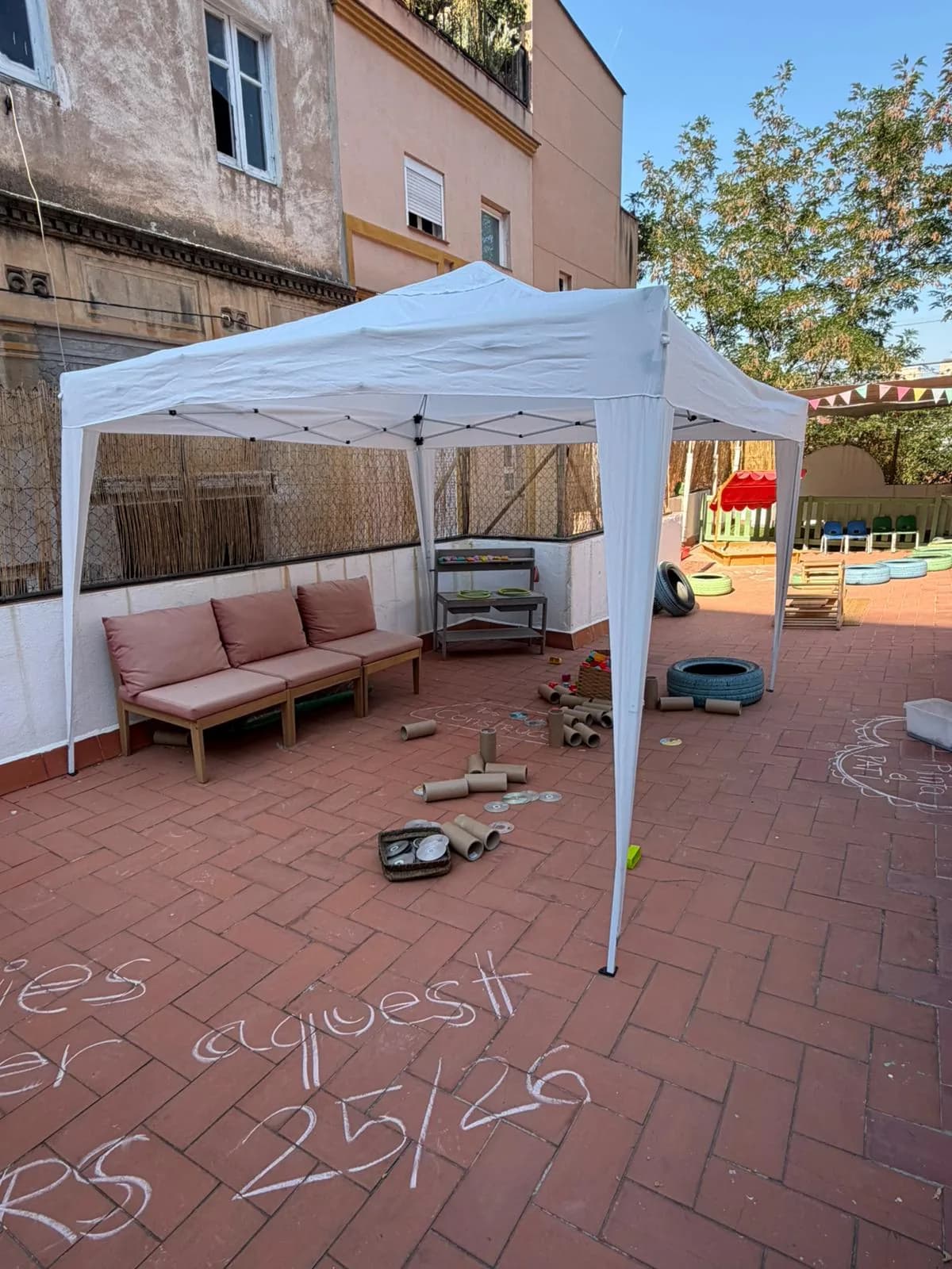 Carpa plegable blanca fent ombra al pati d'una llar d'infants